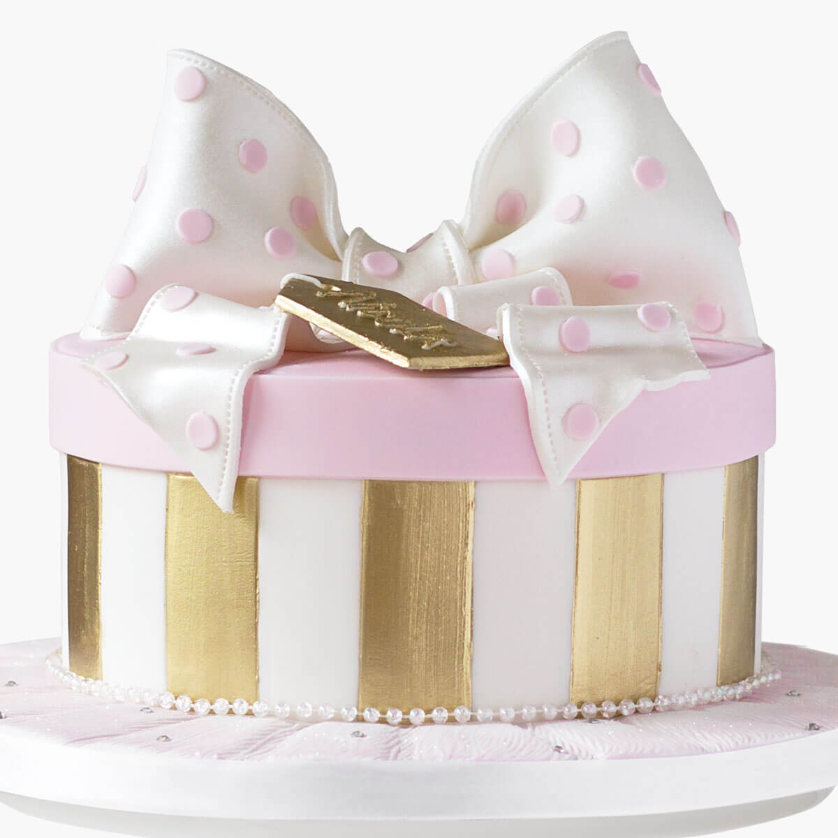 Cake shaped like a gift box complete with lid, bow and gold tag on top