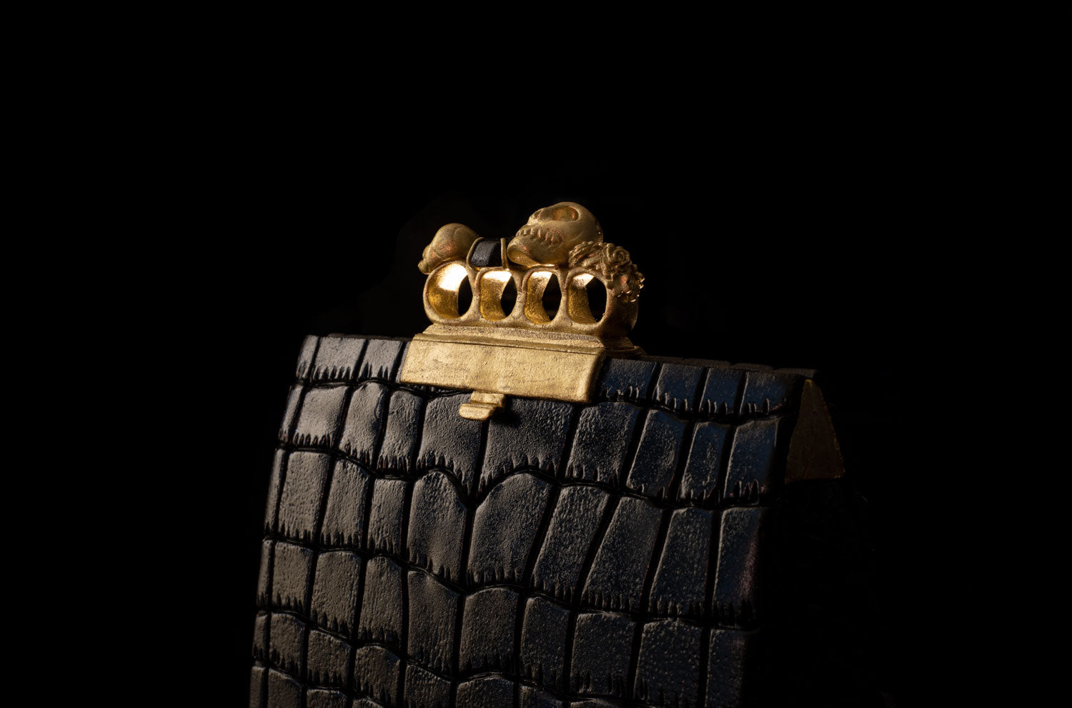 Alexander McQueen knuckle clutch handbag cake. The handbag cake is enveloped in a black fondant leather-like shiny finish. Finished with gold knuckle rings on top.