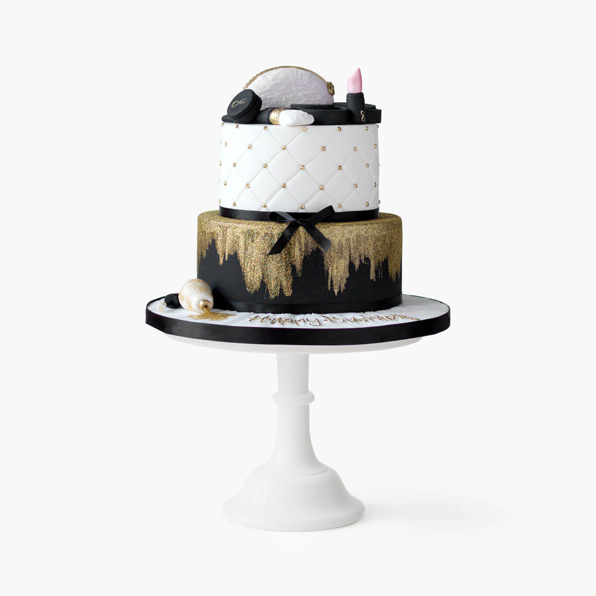 Black and gold makeup cake with gold glitter and quilting decorations. Two tiered cake with edible fondant lipstick, eye shadow palette, mirror, mini makeup bag, makeup brush and nail polish