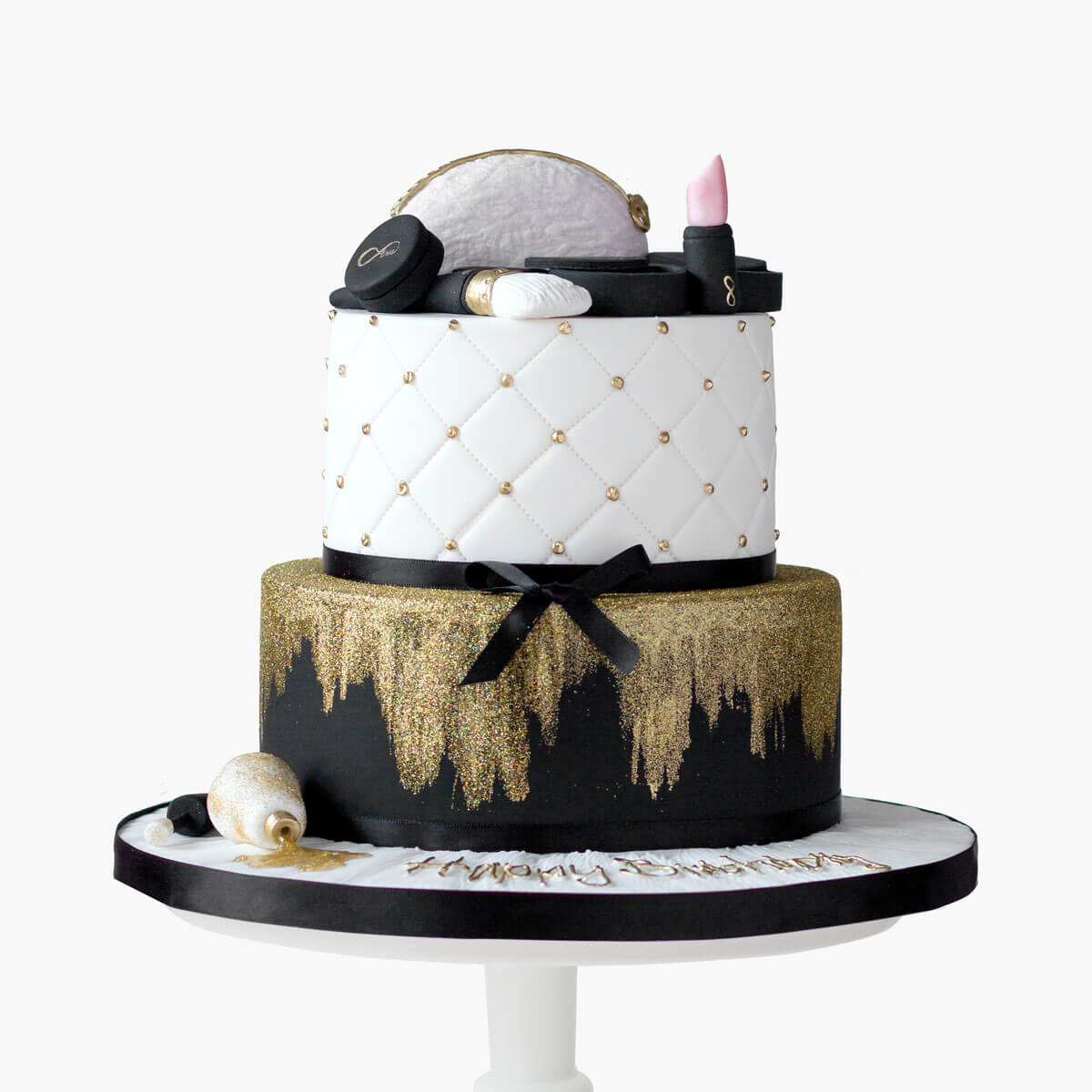 Black and gold makeup cake with gold glitter and quilting decorations. Two tiered cake with edible fondant lipstick, eye shadow palette, mirror, mini makeup bag, makeup brush and nail polish