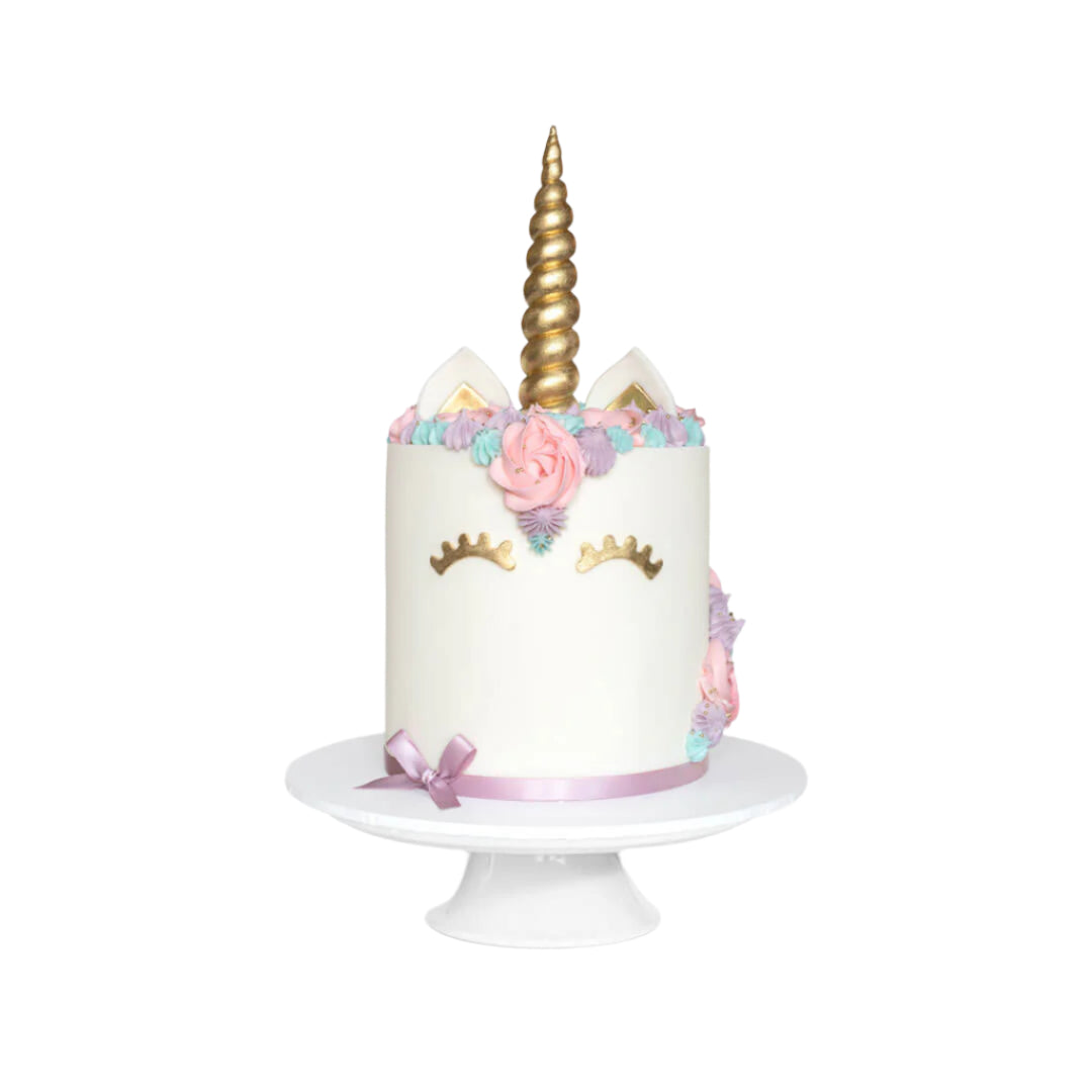 Child's unicorn cake with a pastel coloured buttercreams, gold sugar horn, fondant ears and closed eyes with lashes