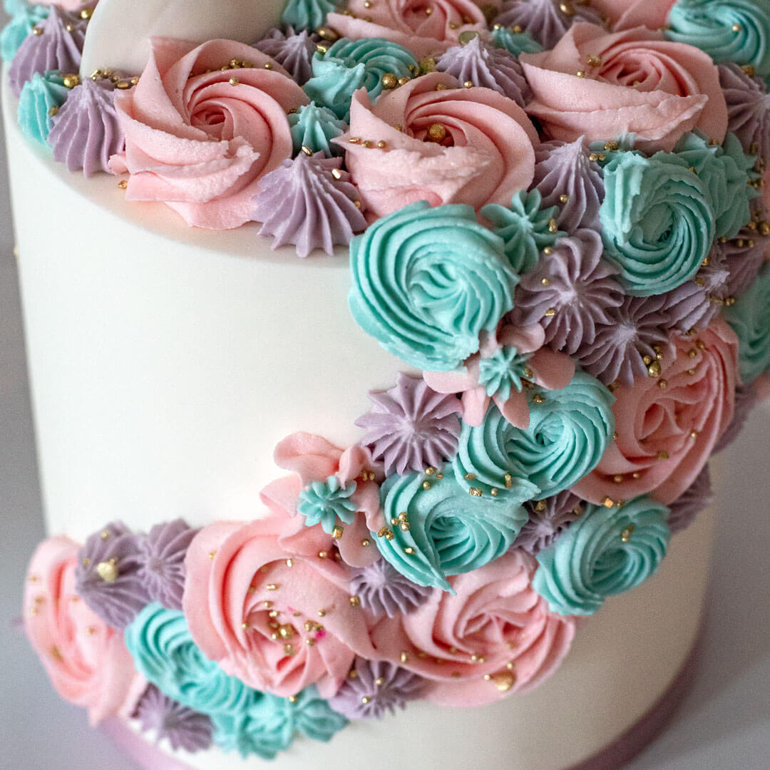 Child's unicorn cake with a pastel coloured buttercreams, gold sugar horn, fondant ears and closed eyes with lashes