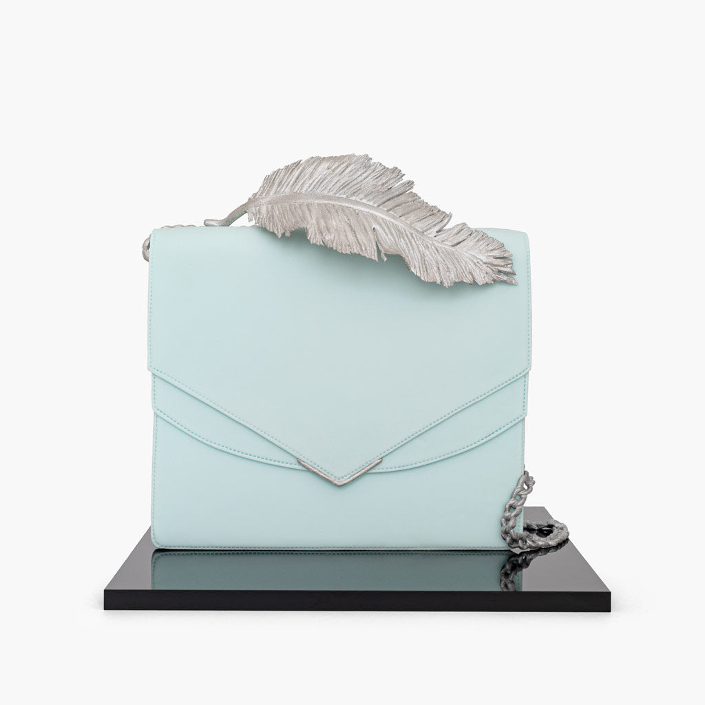 Ralph and Russo inspired leather handbag cake, is an exquisite fusion of elegance and artistry. The handbag cake is wrapped in smooth baby blue fondant and sculpted to emulate fine leather. Complete with Ralph and Russo’s signature metallic feather detail and precise stitching, this cake is a luxurious centrepiece, perfect for those celebrating style and haute couture.