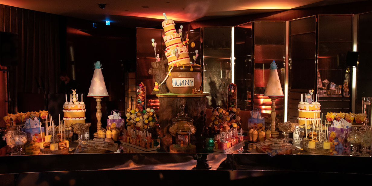 a luxury cake station table with lots of winnie the pooh themed desserts in a knightsbridge hotel