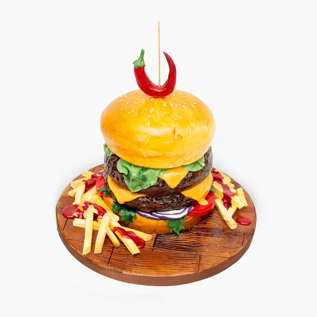 Novelty Burger cake with all the trimmings including cheese, lettuce, red onions and chips, sandwiched between a sesame seeded bun