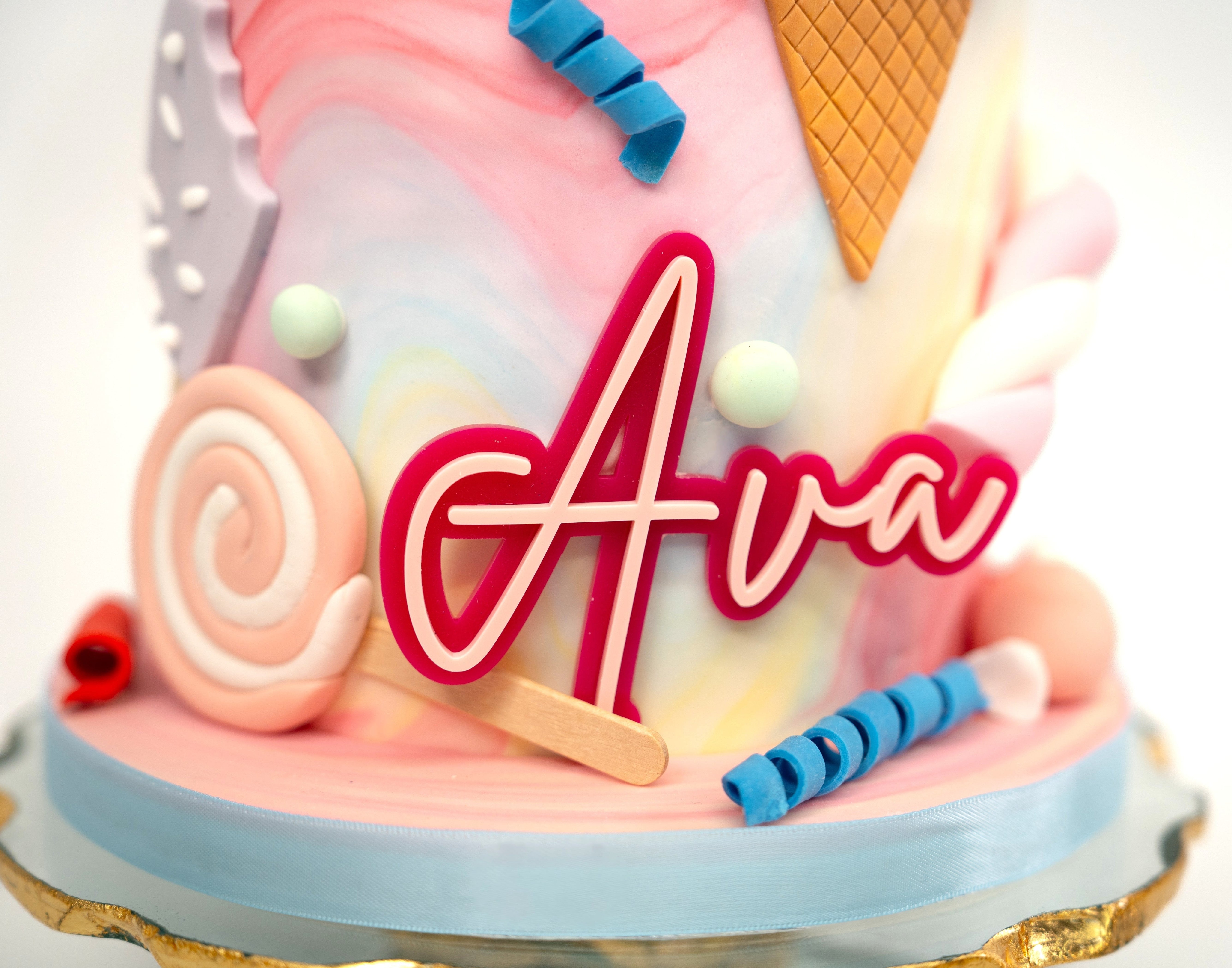 A whimsical Candyland-themed cake with pastel swirls, edible ice cream cones, lollipops, candy twists, and a personalised name plaque and age topper — the perfect centrepiece for any celebration.