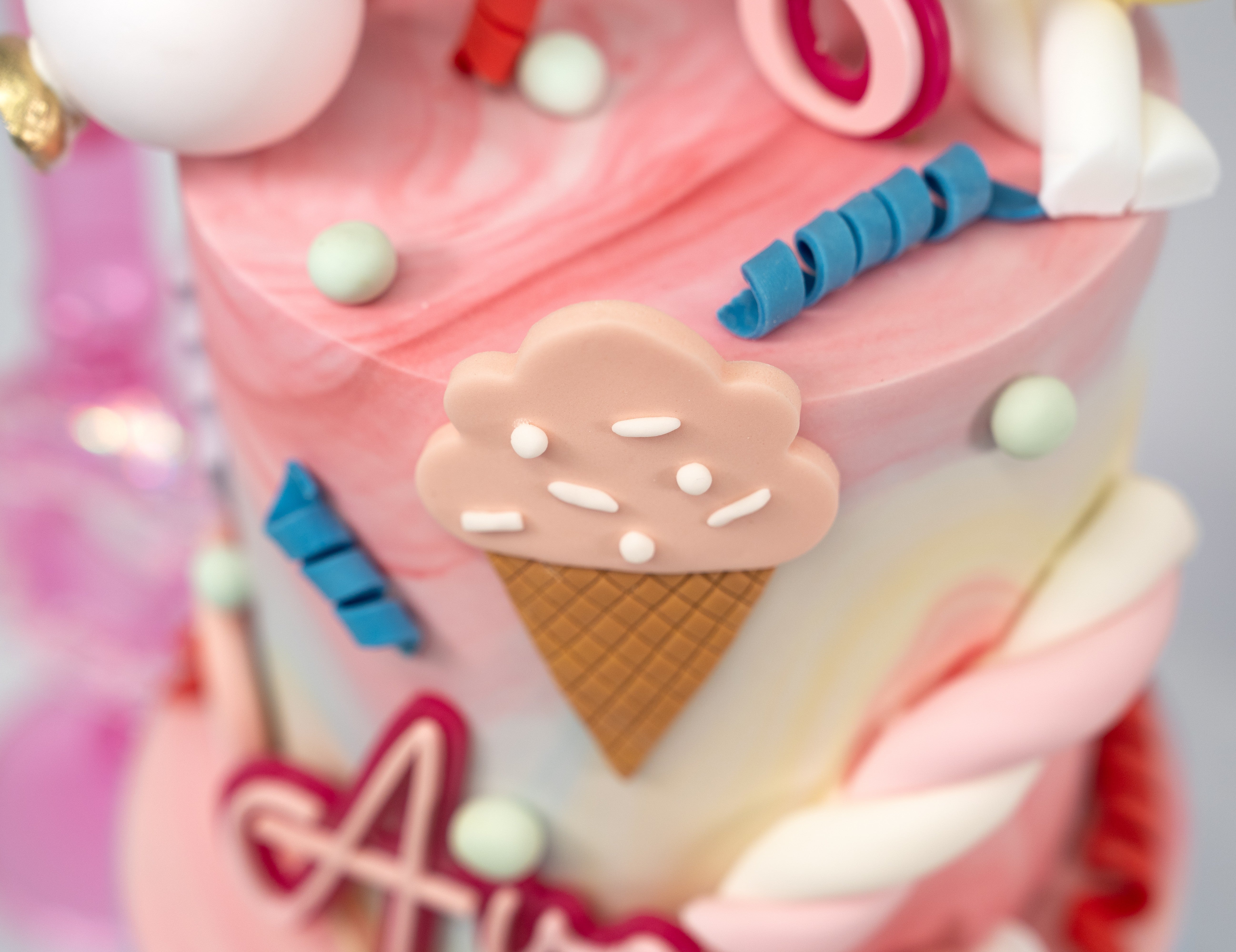 A whimsical Candyland-themed cake with pastel swirls, edible ice cream cones, lollipops, candy twists, and a personalised name plaque and age topper — the perfect centrepiece for any celebration.