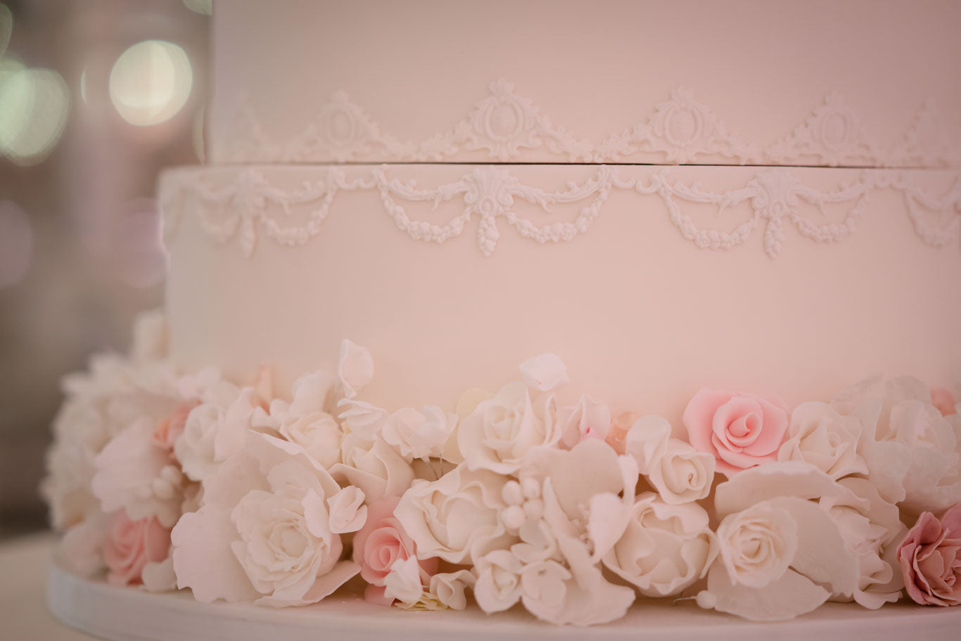 pale pink wedding cake detailed with white and pink icing flowers round the base