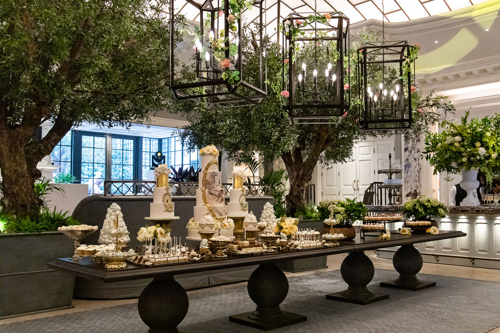 a large gold and white desert bar of cakes and cookies on display at a private event