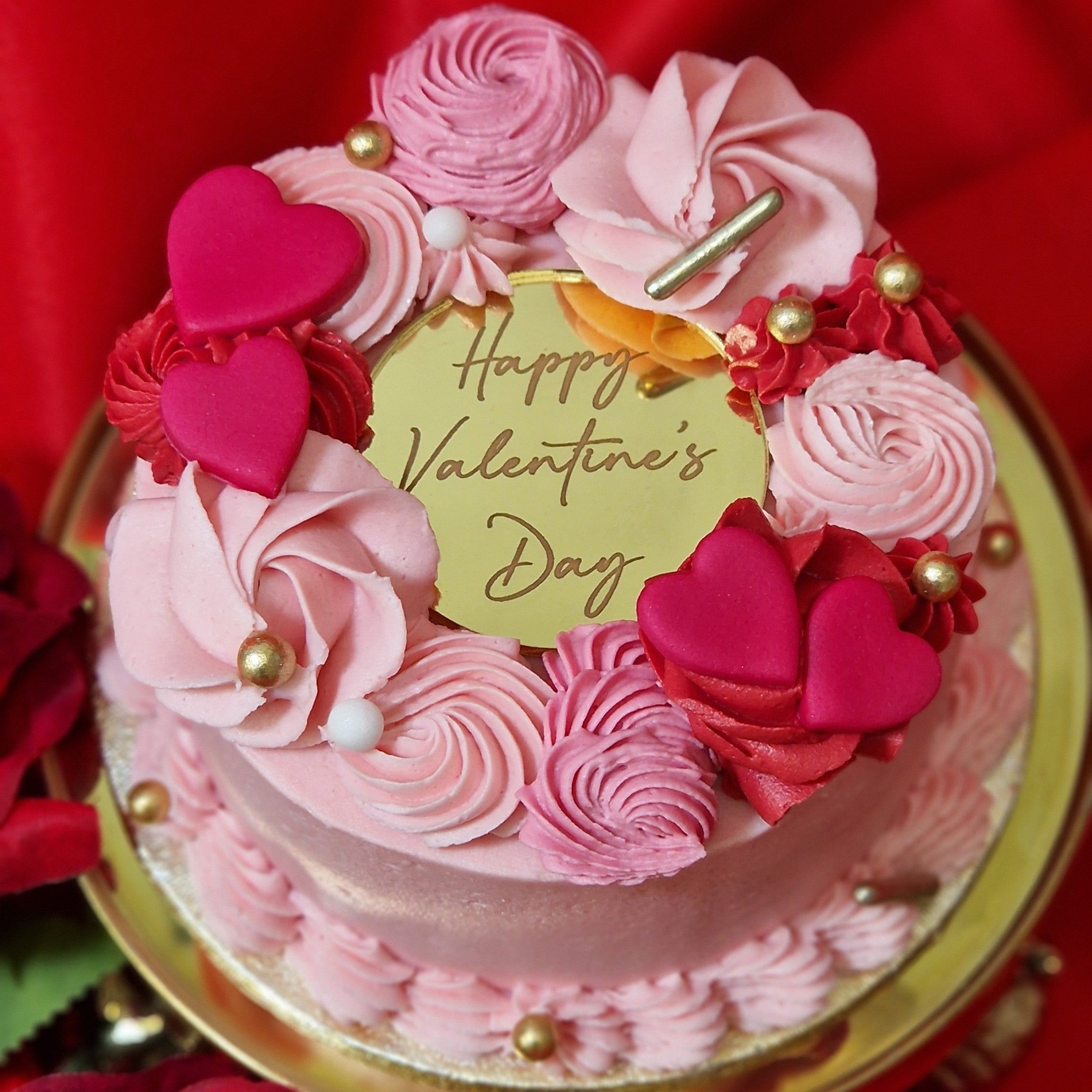 Valentines Day themed Bento Box with pink buttercream mini cake decorated with buttercream swirls and fondant hearts, accompanied by 2 red velvet cupcakes