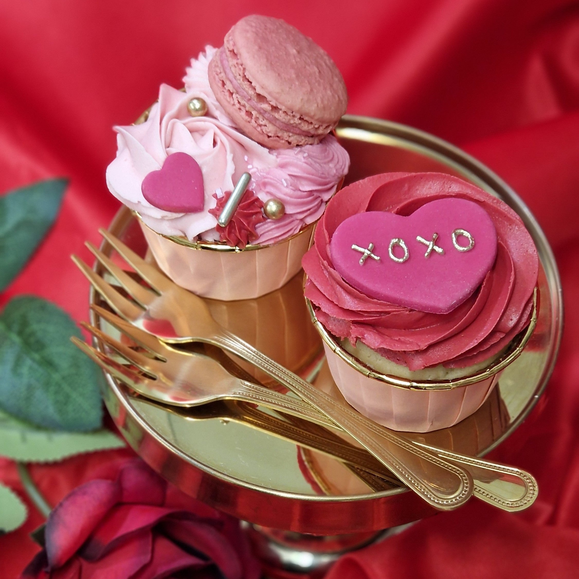 Valentine's Bento Box featuring a pink buttercream mini cake with heart decorations and buttercream swirls, accompanied by 2 cupcakes decorated with macaron, fondant hearts and gold sprinkles