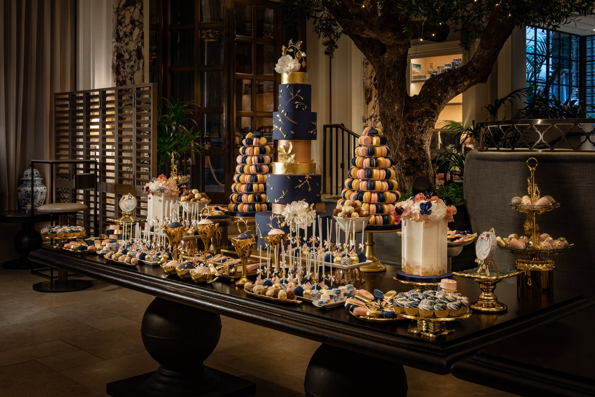 long brown table with wedding cake dessert station in blush gold and blue