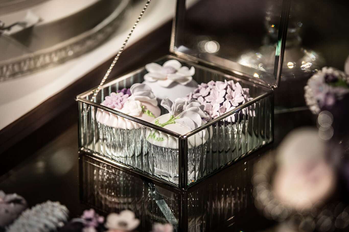 four elegant flower wedding design cupcakes in an open glass box display