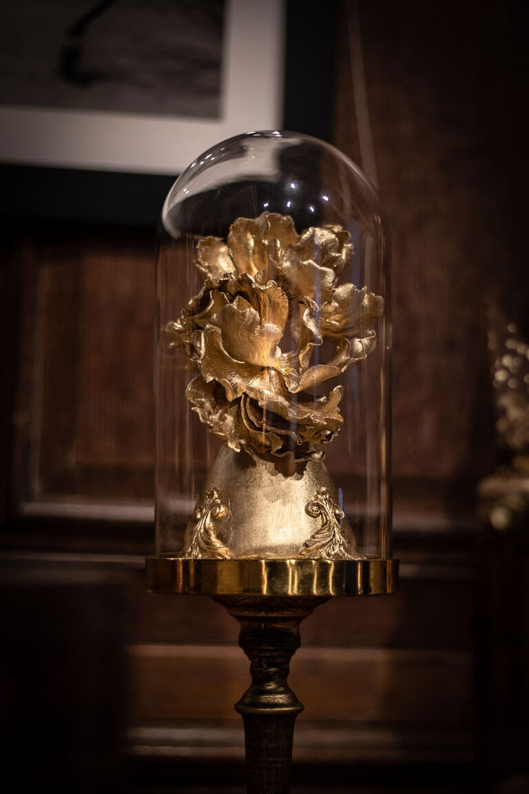 a luxury gold flower made out of sugar encased in a cloche at an event in london