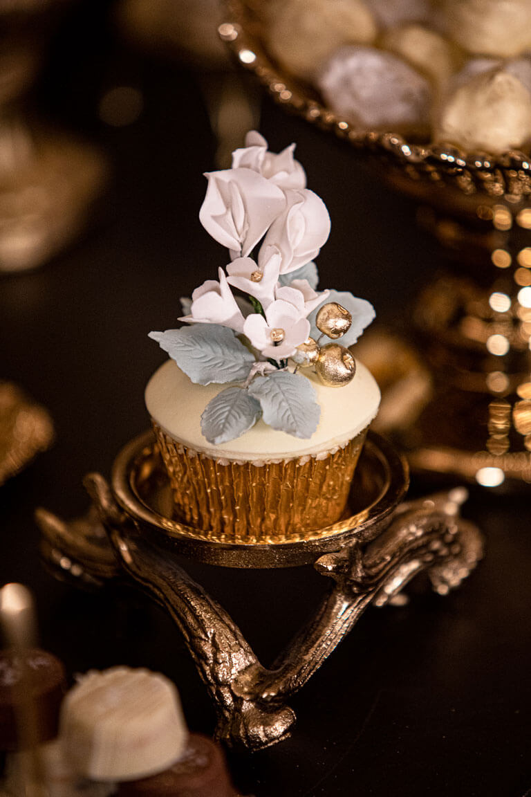 single cupcake with intricate elegant flower design displayed on a desert table in london at a private event