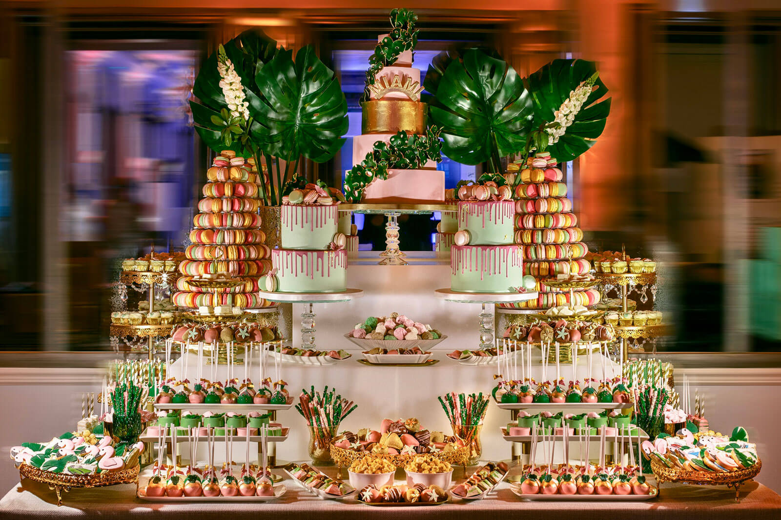 miami themed luxury dessert table full of cakes, macarons, cookies