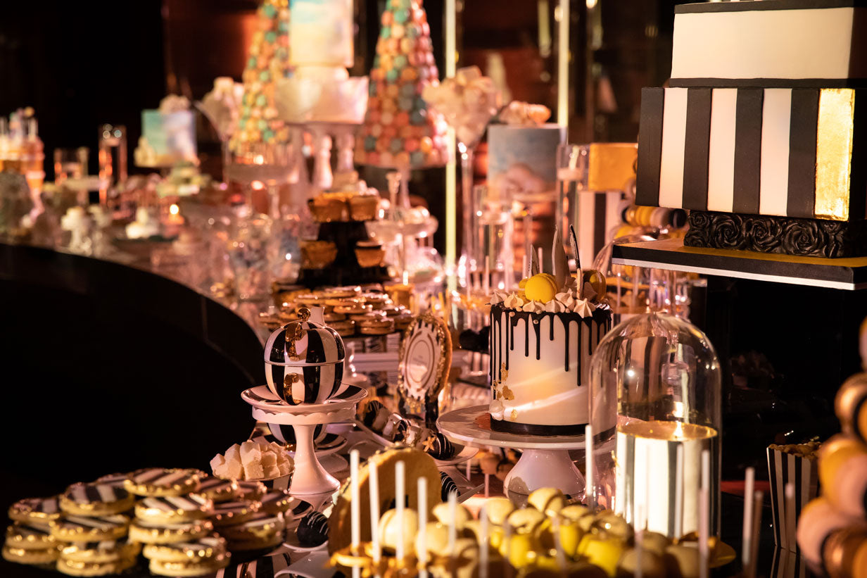 a dessert station full of luxurious black gold and white desserts