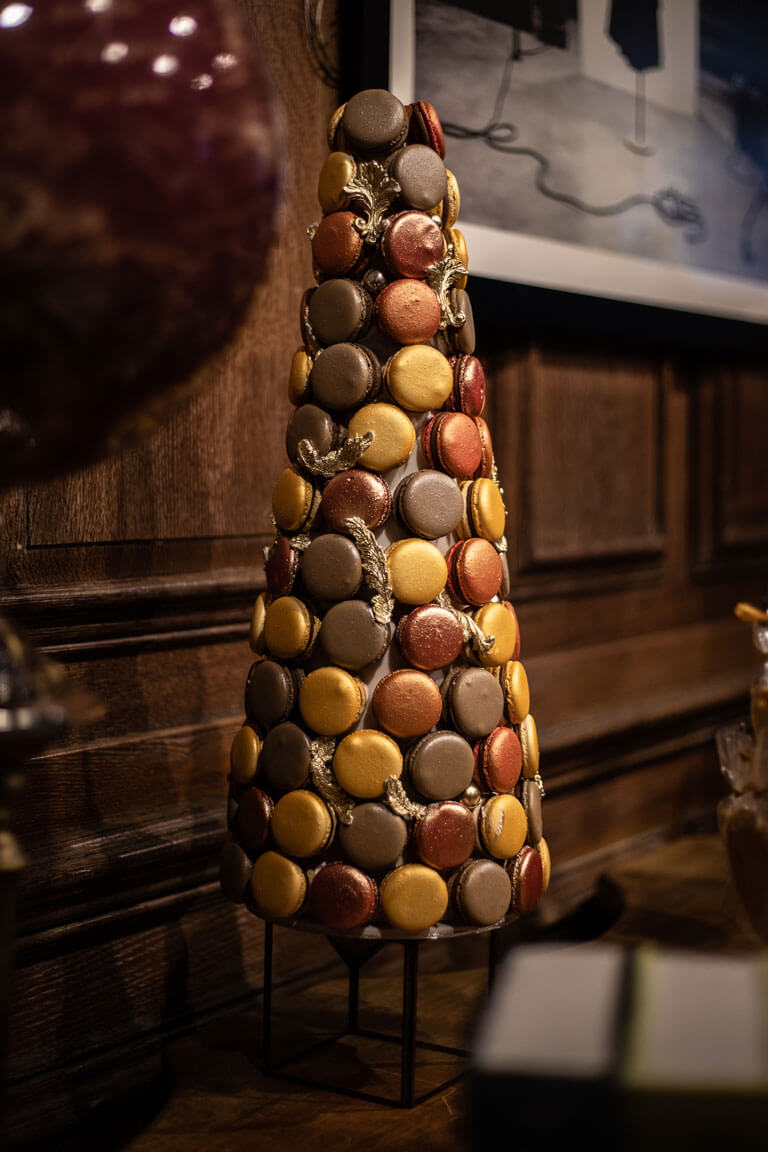 a tower of gold and brown macarons on a desert bar at a private london event in an high end book store