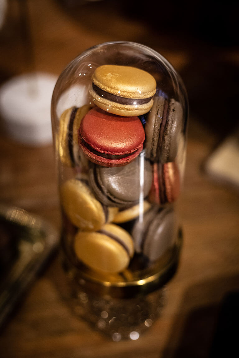 a selection of autumnal coloured macarons encased in a cloche on a desert table