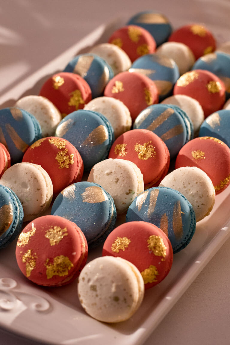 luxury red blue and white gold leaf design macarons on a white tray