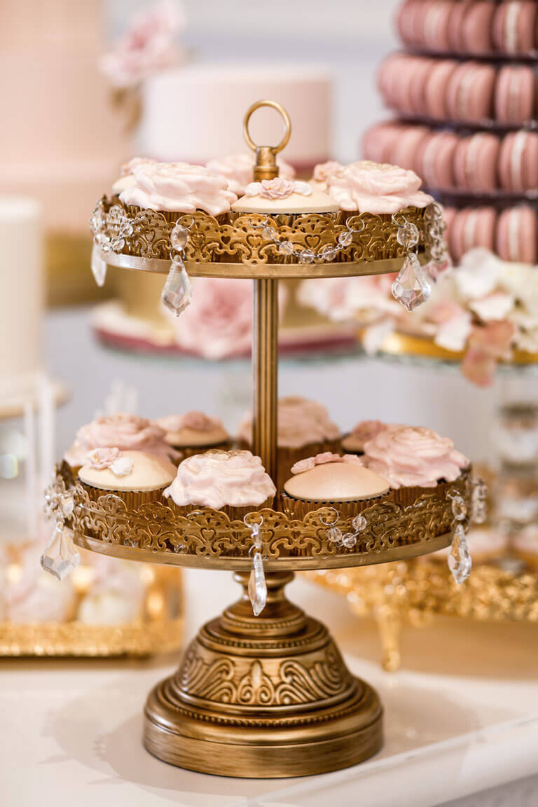 blush pink cupcakes on a two tier gold cake stand at a luxury wedding