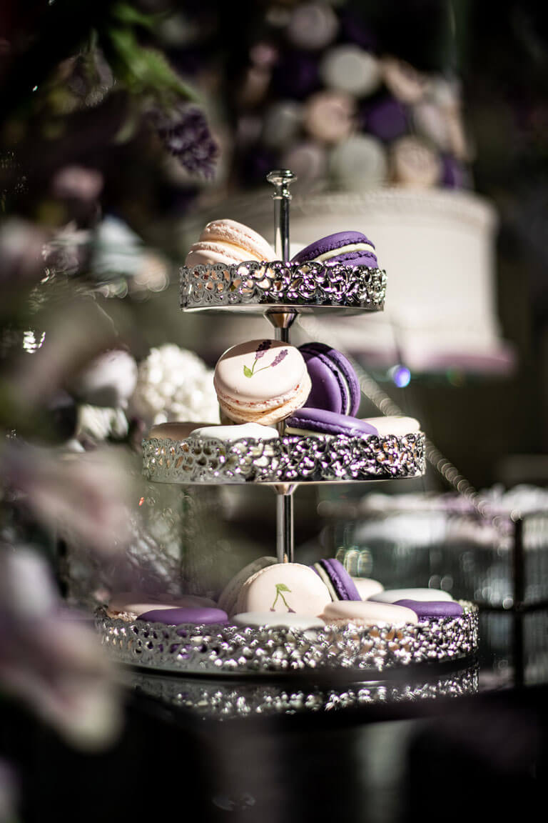 bespoke purple and white macarons displayed on a cake stand for a wedding