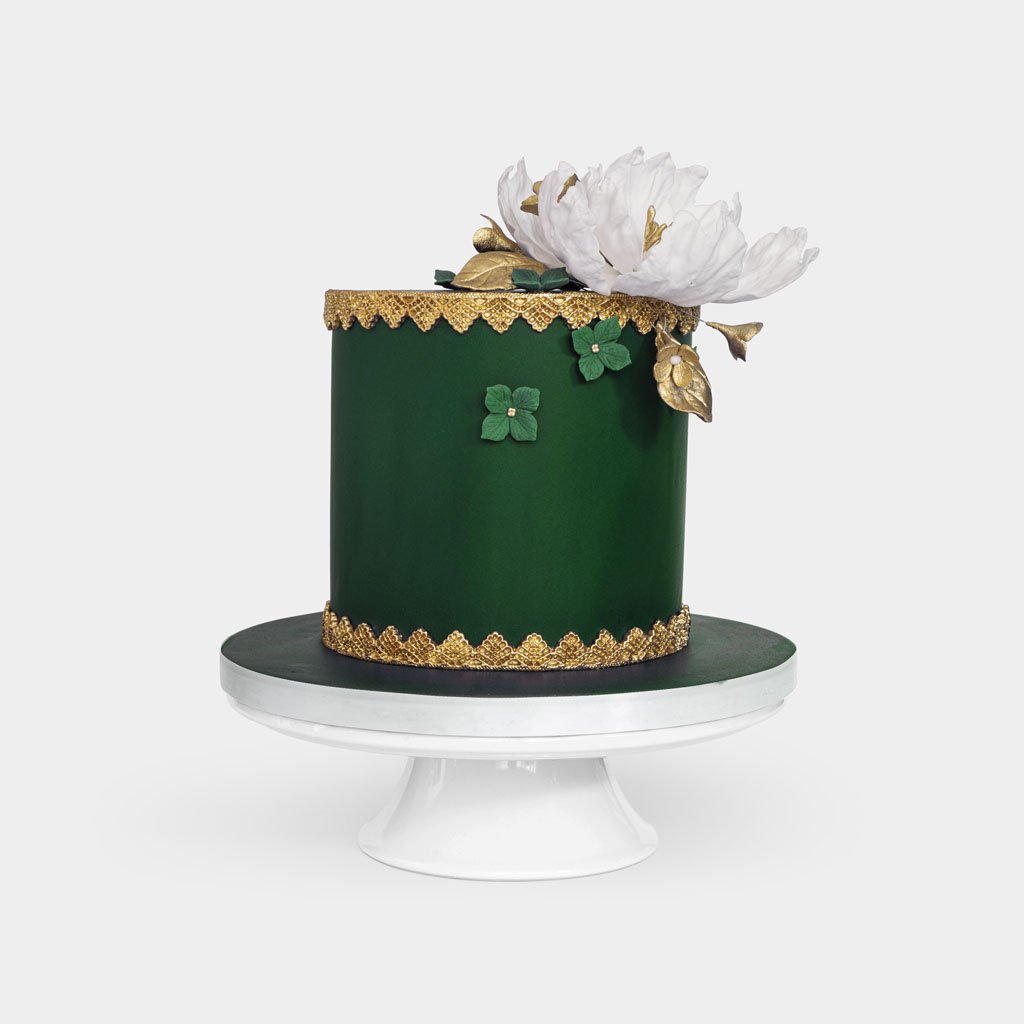 Luxurious green fondant cake with gold lace detailing, large white peony with gold leaves topper