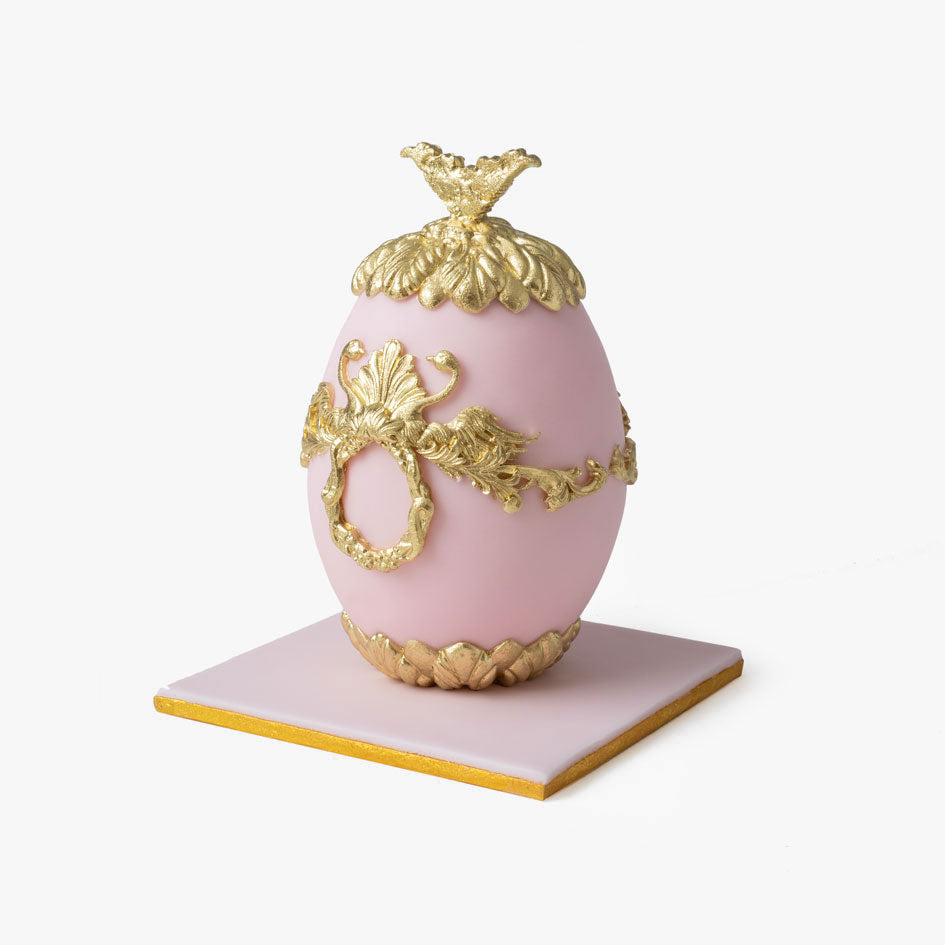 Pink Faberge cake egg with ornate gold decorations and crown