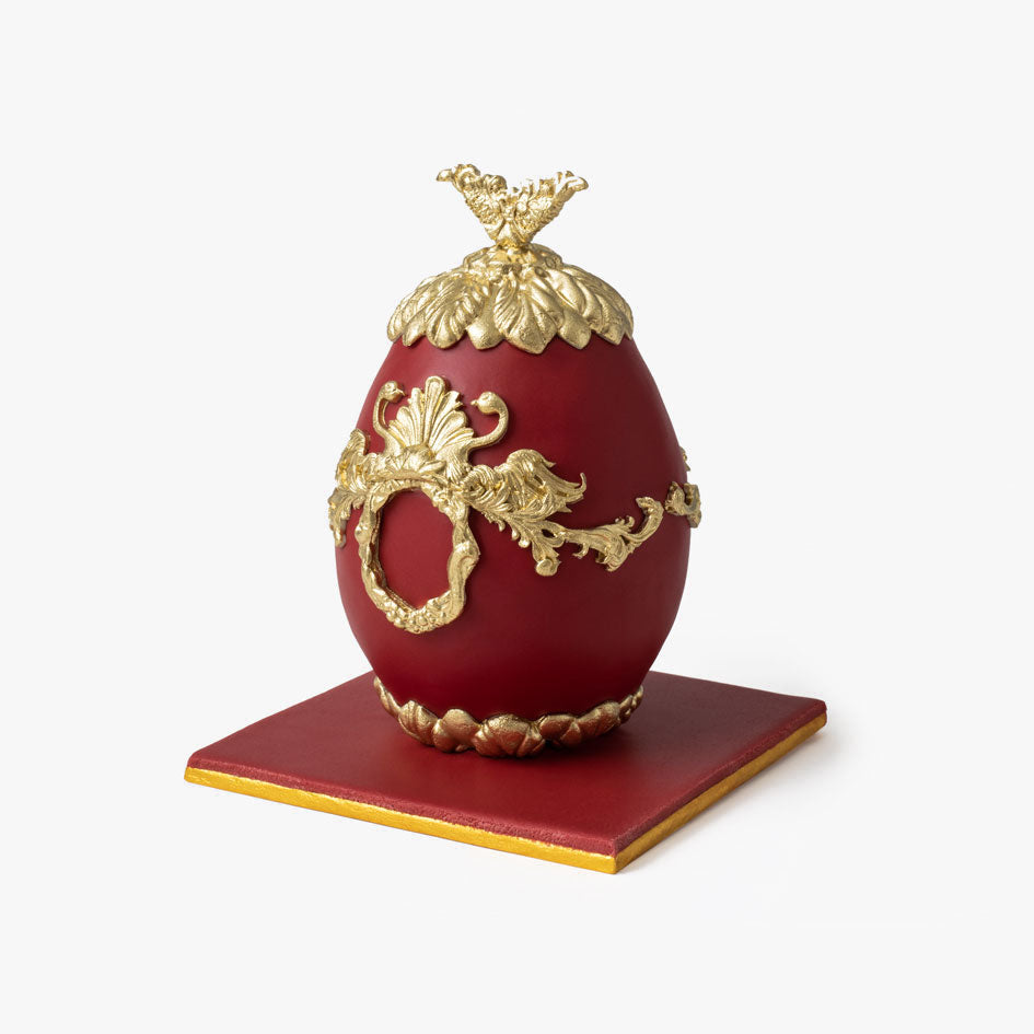 Red Faberge cake egg with ornate gold decorations and crown