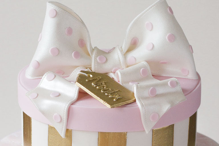 Cake shaped like a gift box complete with lid, bow and gold tag on top