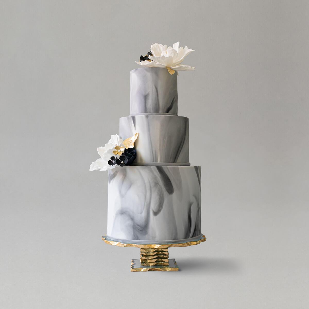 3-tier grey marble wedding cake with white sugar flowers and subtle black and gold accents