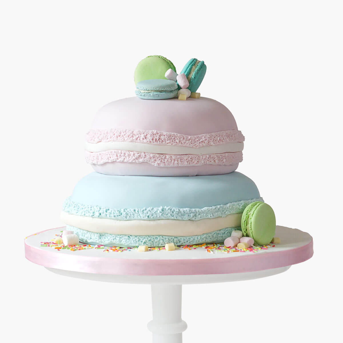 Two tiered pink and blue macaron themed cake with actual macarons as toppers amd side decorations