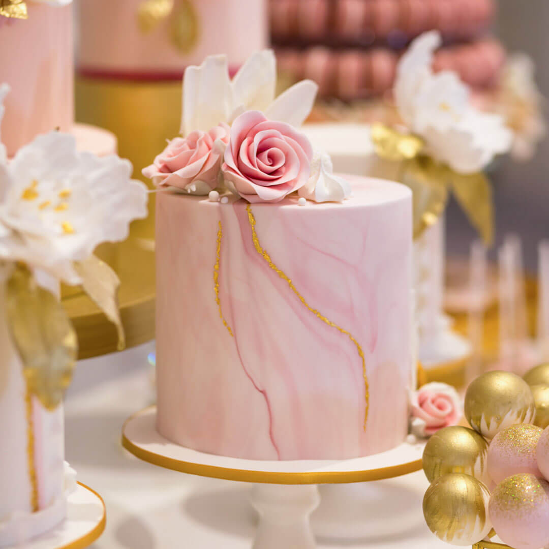 Pink marble cake with cluster of handcrafted sugar flowers and sweet treats on top