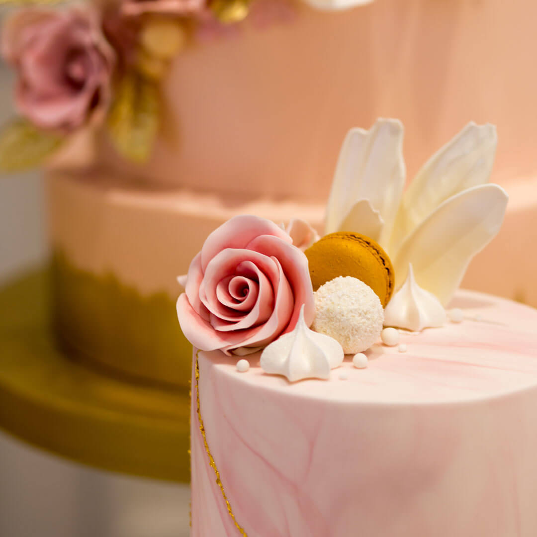 Pink marble cake with cluster of handcrafted sugar flowers and sweet treats on top