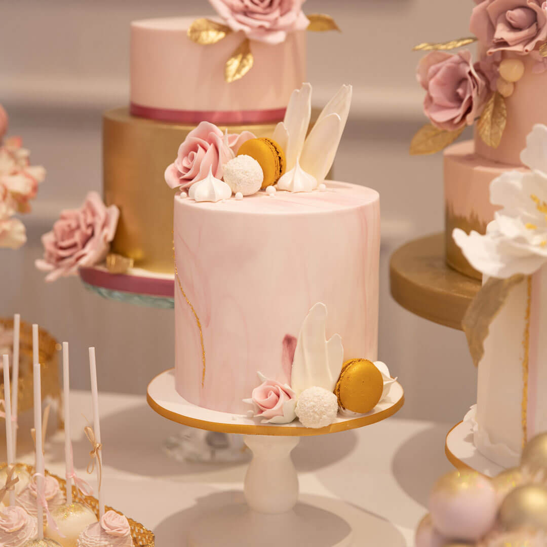 Pink marble cake with cluster of handcrafted sugar flowers and sweet treats on top